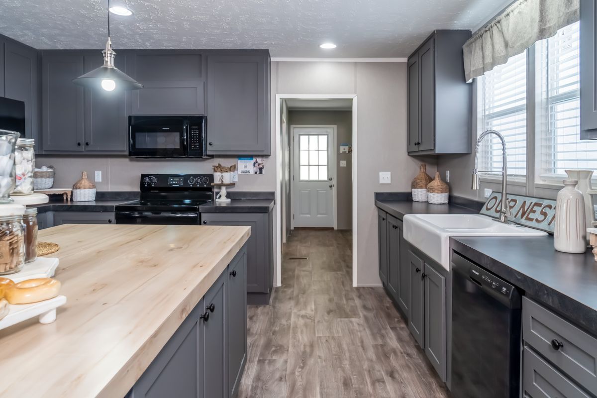 57b13a7e-c863-4456-ad4f-c3e751a9e188 A kitchen with gray cabinets and black counter tops, elegantly combining contrasting colors.