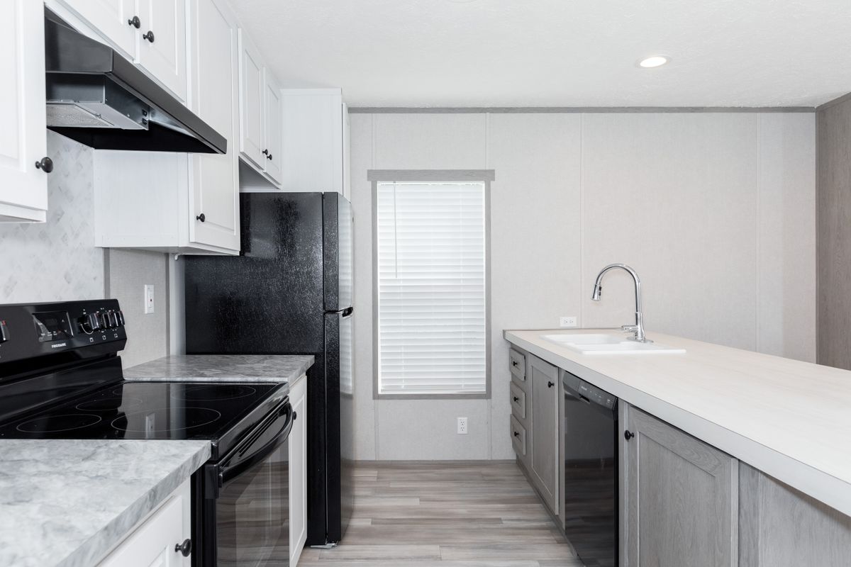 5898999e-b605-43c7-adfb-6a916d600e3f A kitchen in a mobile home with white counter tops and stainless steel appliances.