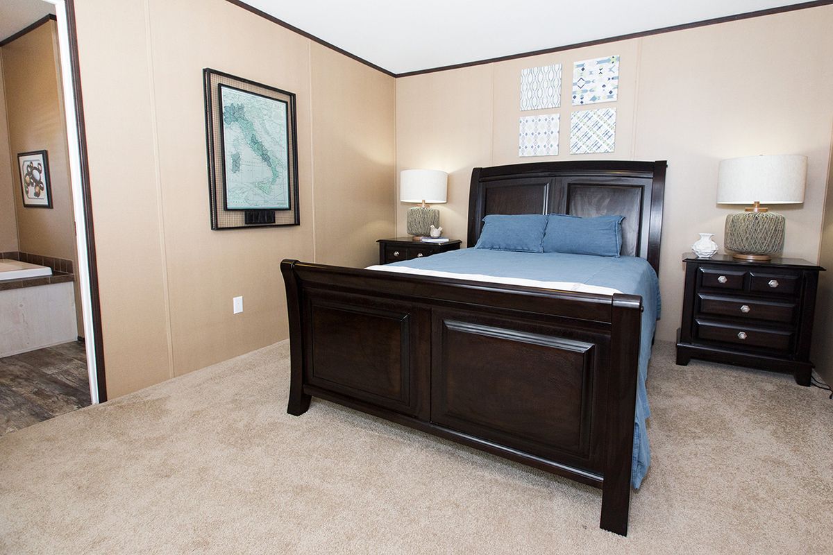 null A bedroom in a mobile home with a bed and a bathtub.