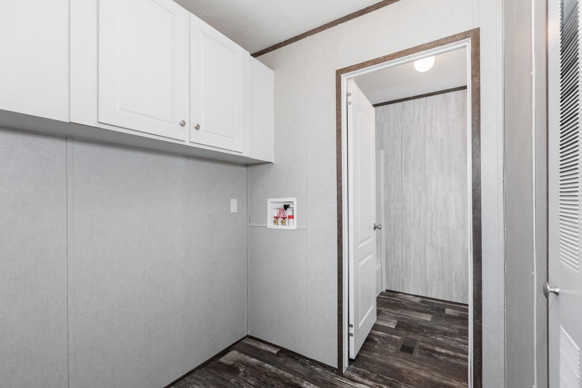 A small room with white cabinets and wood floors.