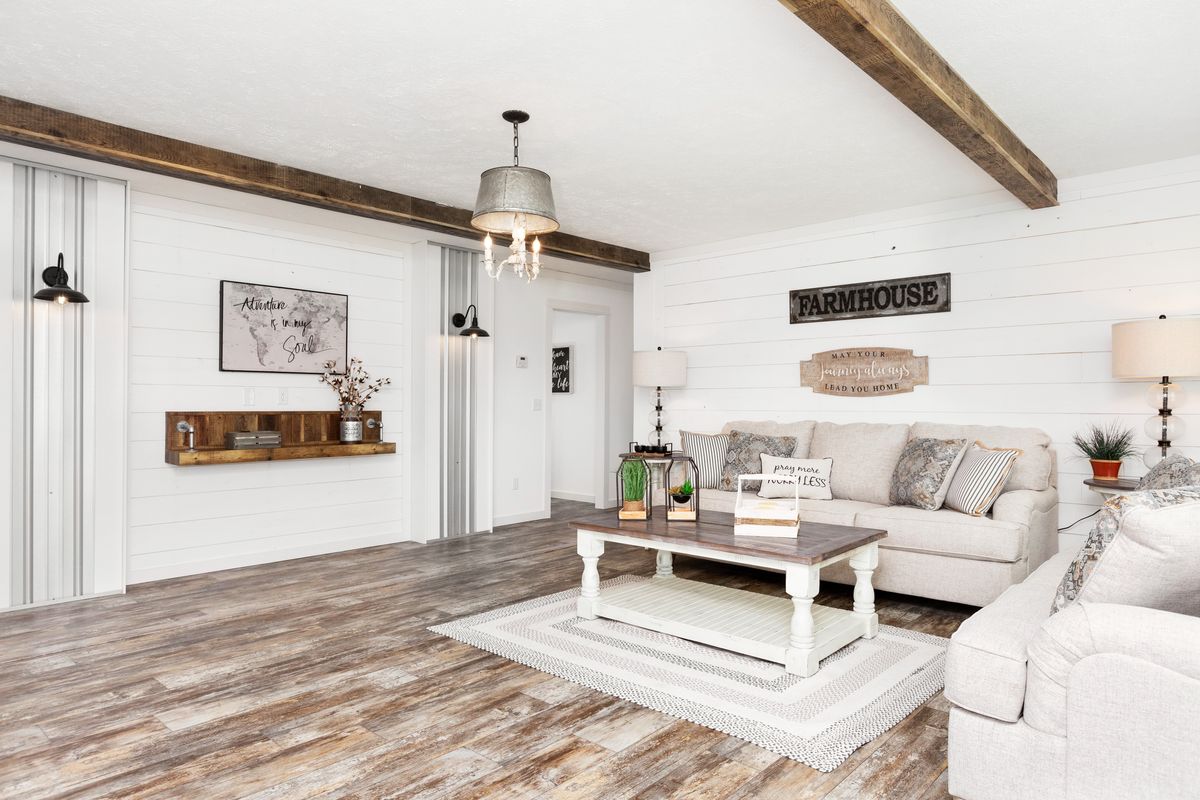 A living room with white walls and wood beams.