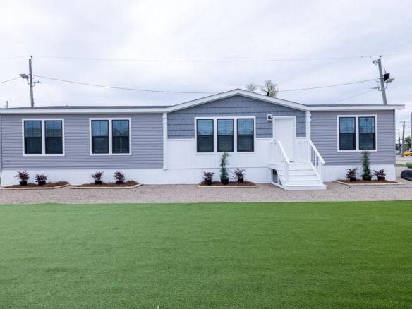 A mobile home with grass in front of it.