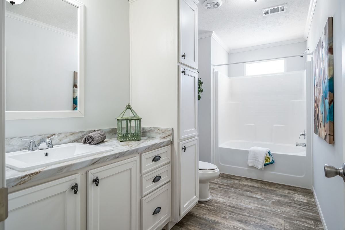 680b069b-4d39-49f4-b443-eb9e17e0f015 A bathroom with white cabinets and wood floors.
