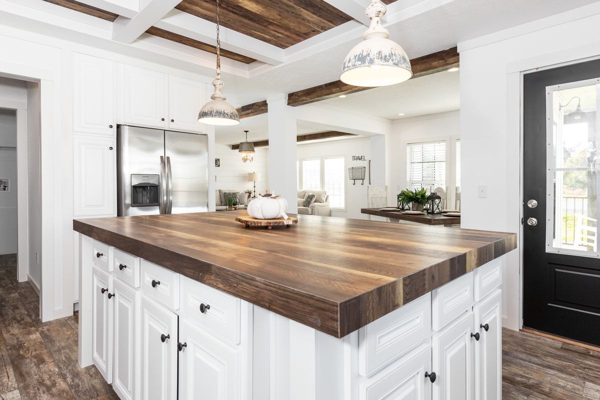 A white kitchen with wood floors and a wooden island.
