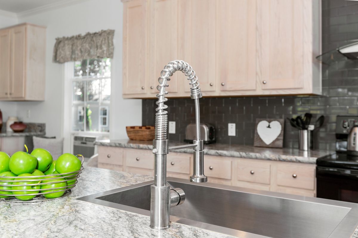 A kitchen with a stainless steel sink and green apples.