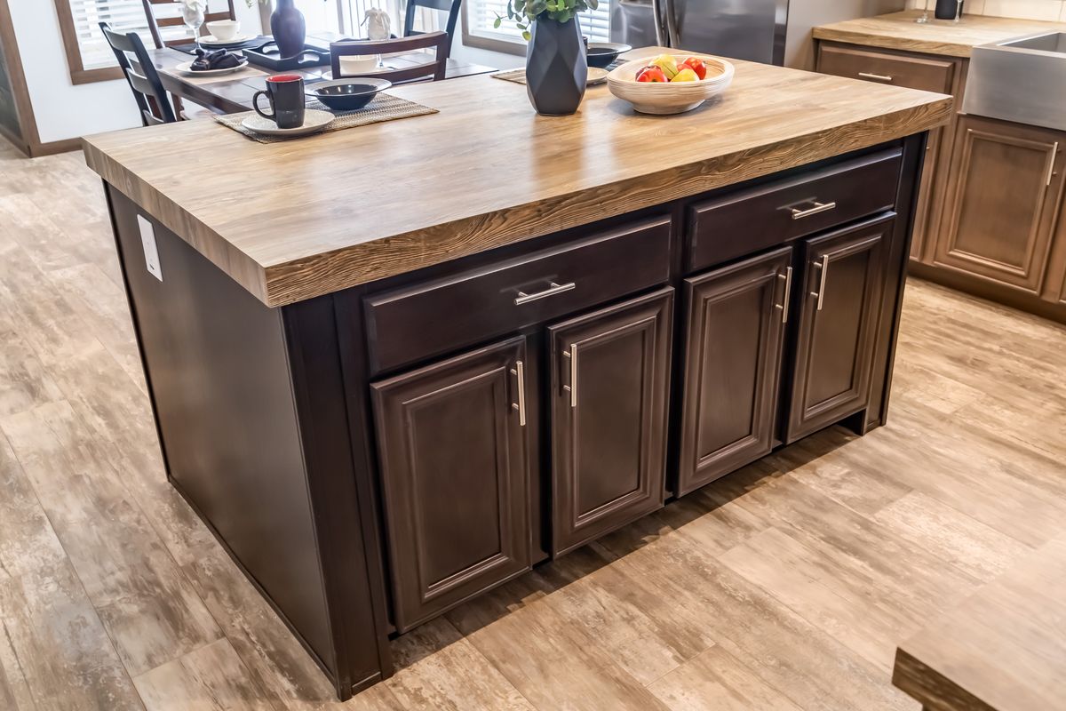 A kitchen with a large island and wood floors.