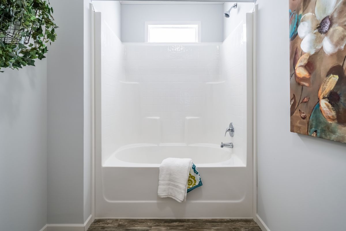 6beb385d-3a0e-4739-a42d-48baf9e794ed A bathroom with a white tub and a wooden floor.