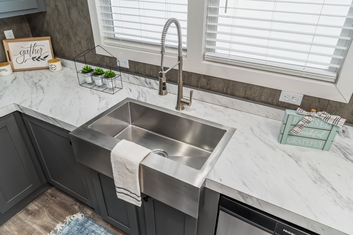 6e085378-7af9-4691-ba8a-14e3d8c1be4f A kitchen with a stainless steel sink and granite counter tops.