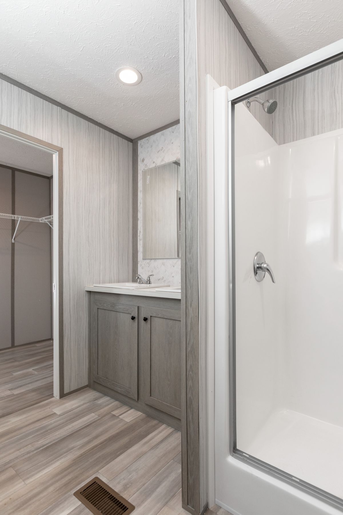 6fc3688d-131c-4853-aea8-f322e749314e A bathroom in a mobile home with a walk in shower.