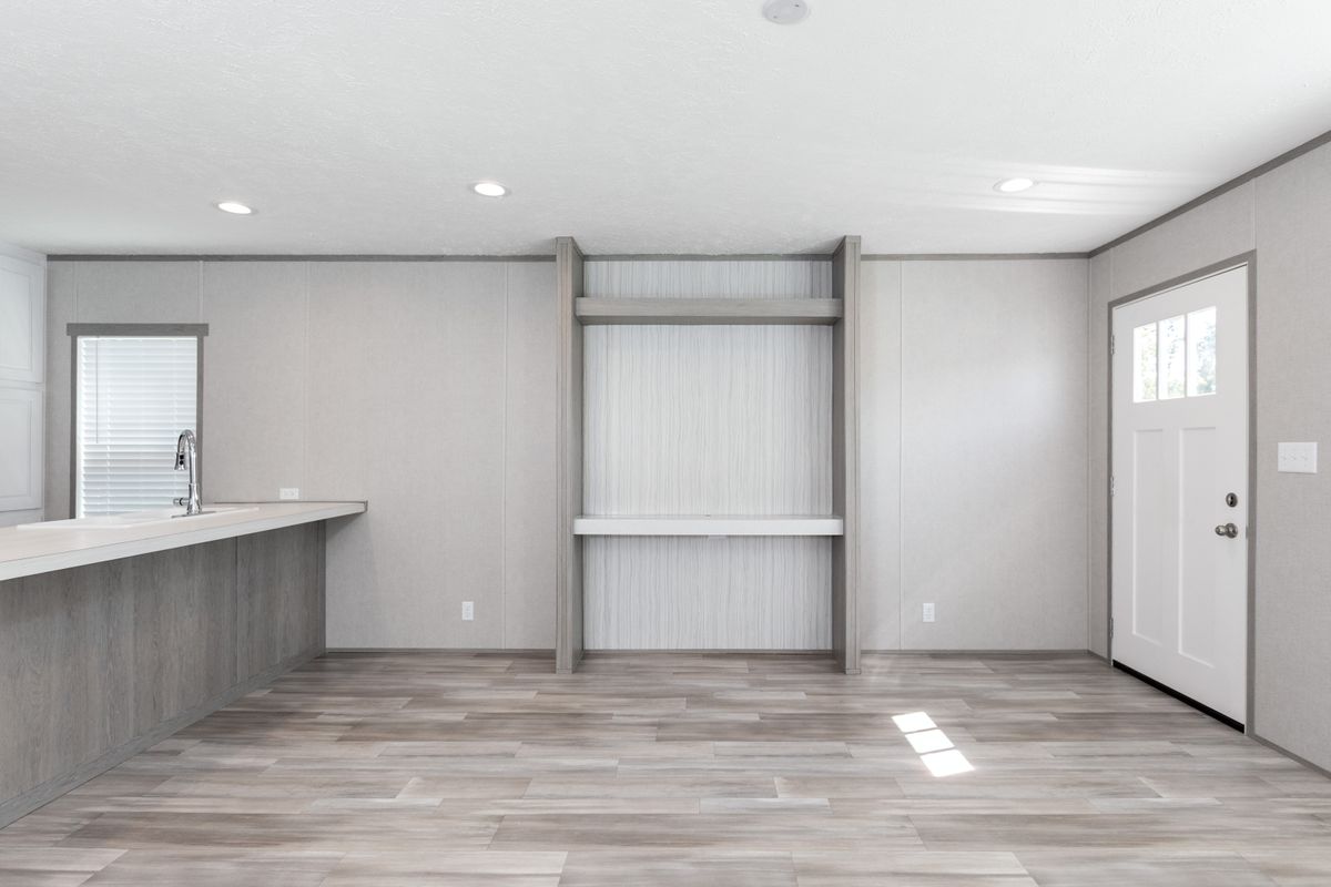 7162de63-eccd-41fe-b361-9bdba89d5ed9 An empty living room with wood floors and white walls.