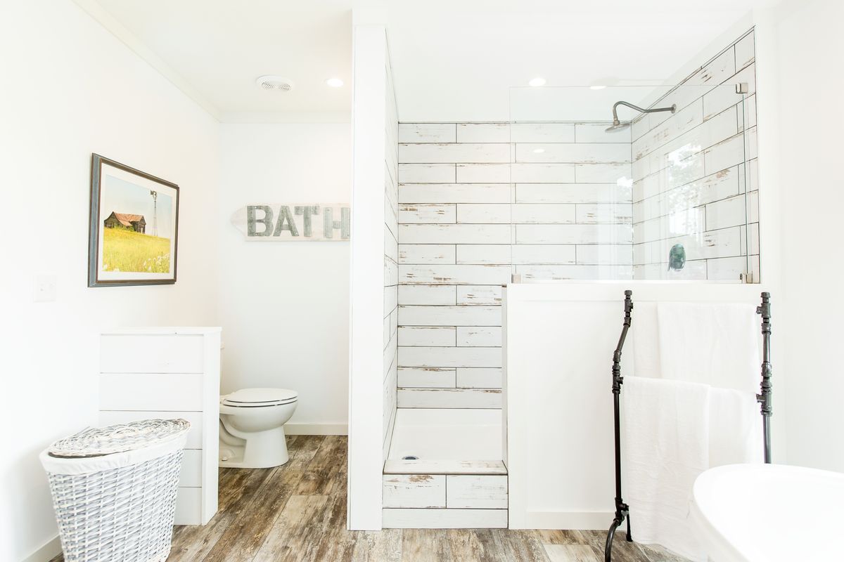 A white bathroom with wood floors and a toilet.