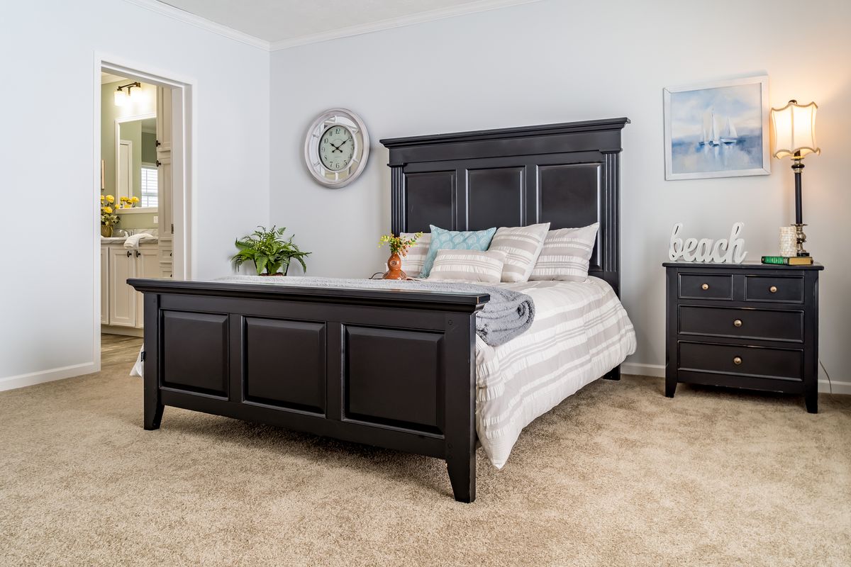 77479db2-c08b-4287-b8c0-b5a2ddf79687 A bedroom with a black bed and dresser.
