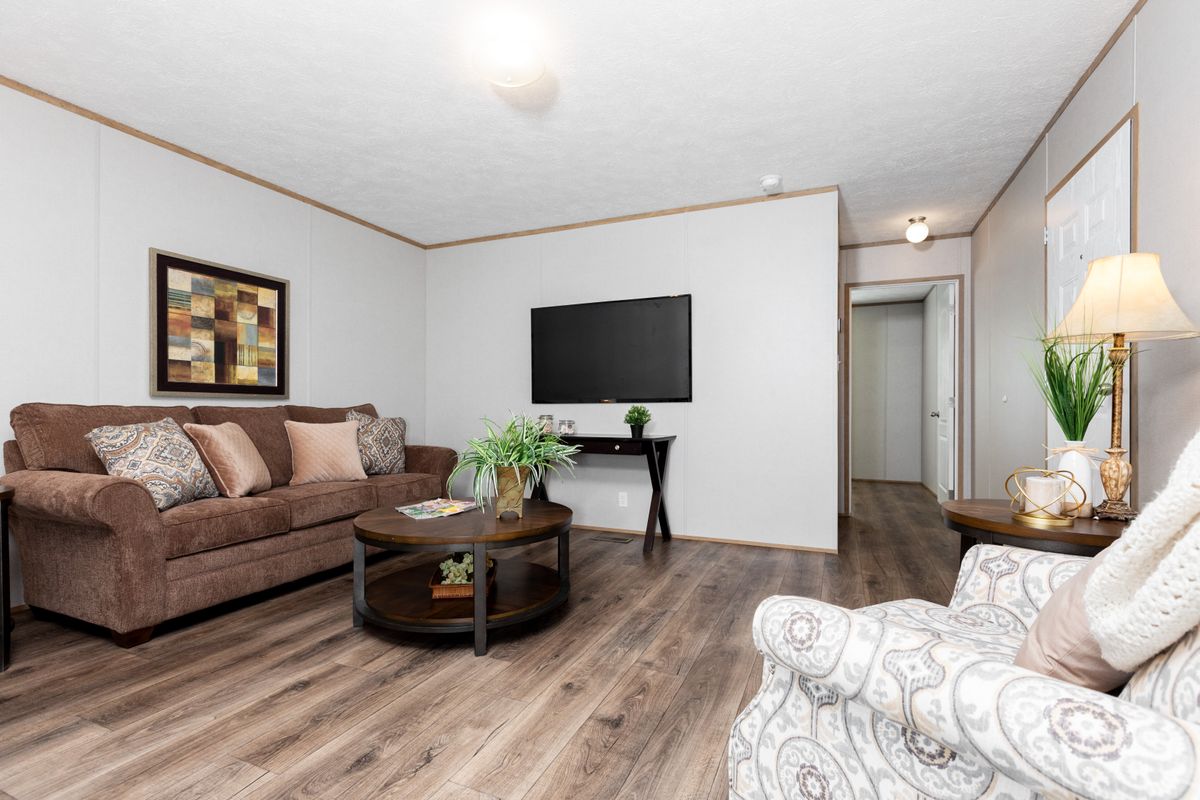 A living room in a mobile home with hardwood floors.