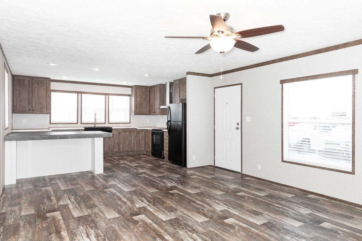 An empty kitchen with wood floors and a ceiling fan.
