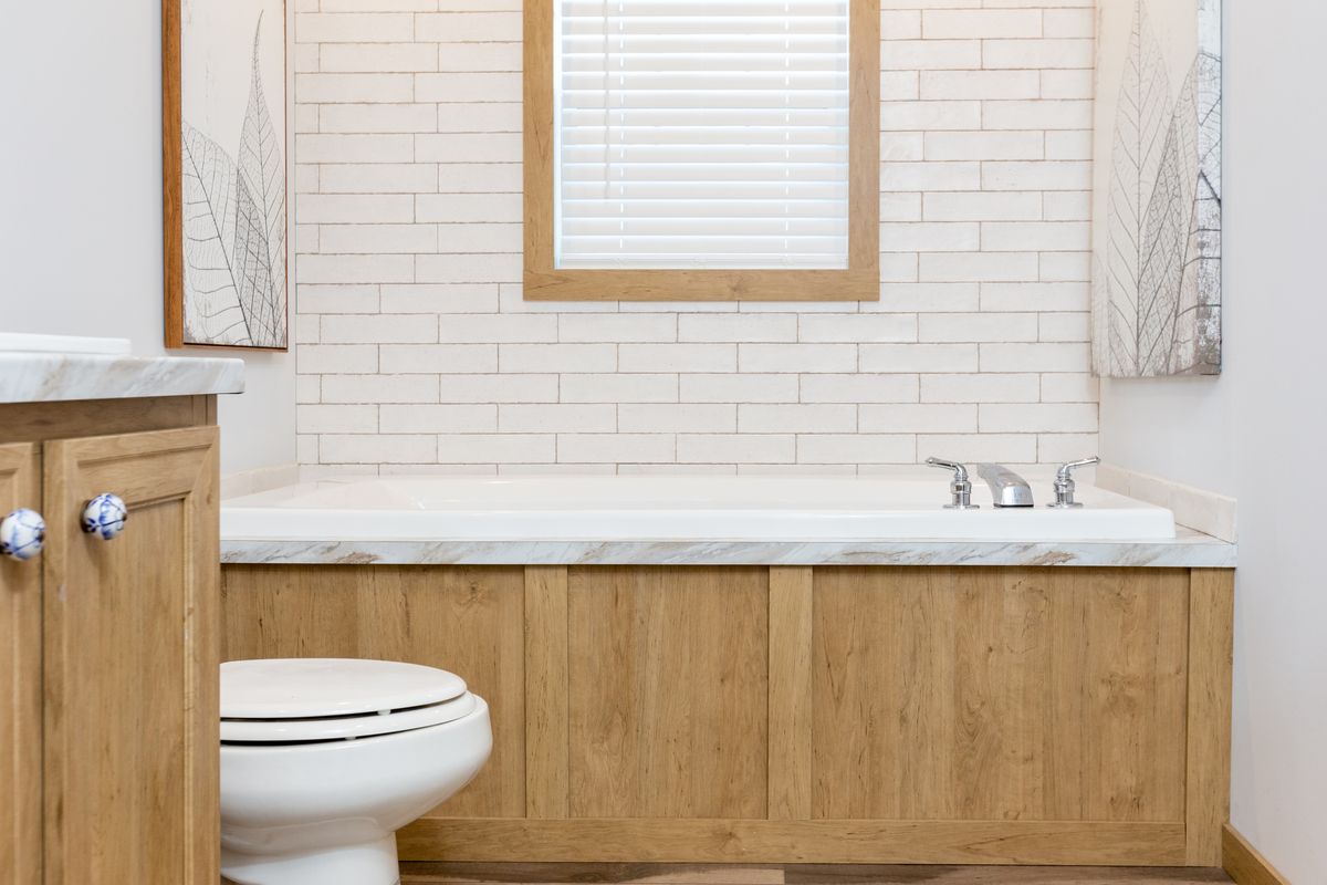 A white bathroom with wood cabinets and a tub.