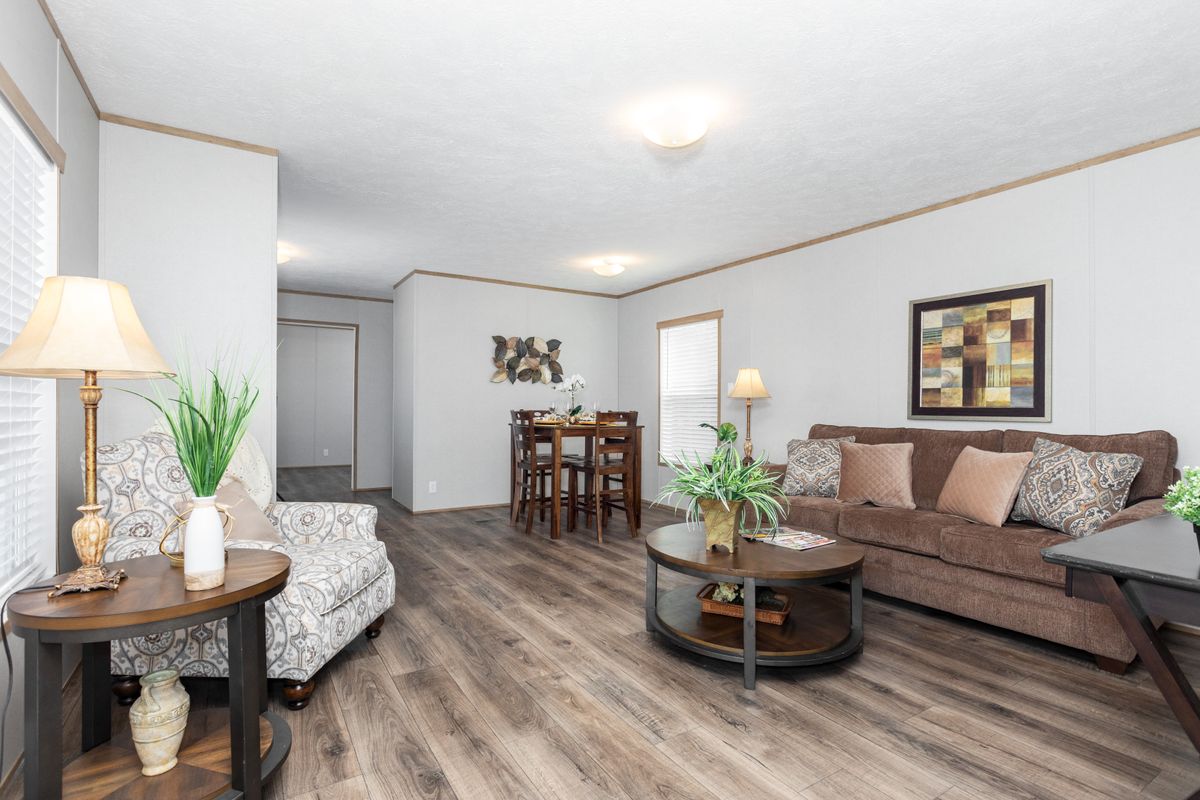 A living room in a mobile home with hardwood floors.