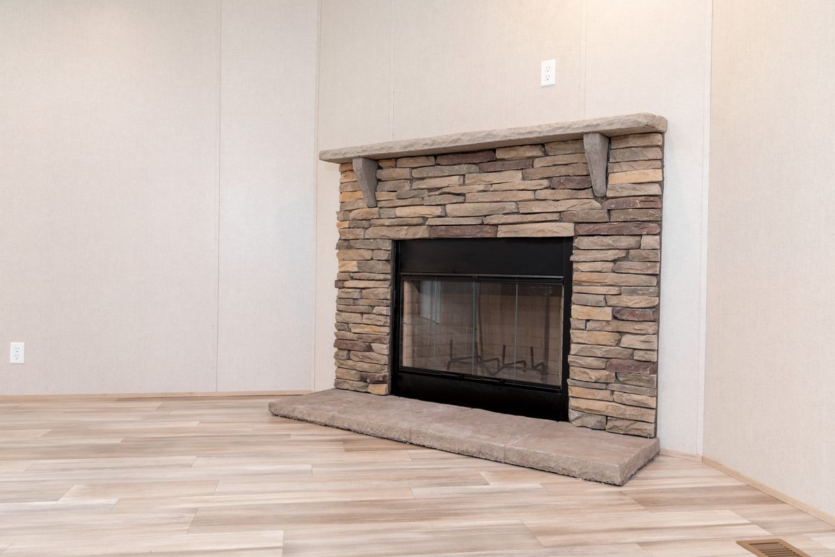 81d765b3-dc00-4a7e-9da5-b942077d355a A living room with a stone fireplace and wood floors.