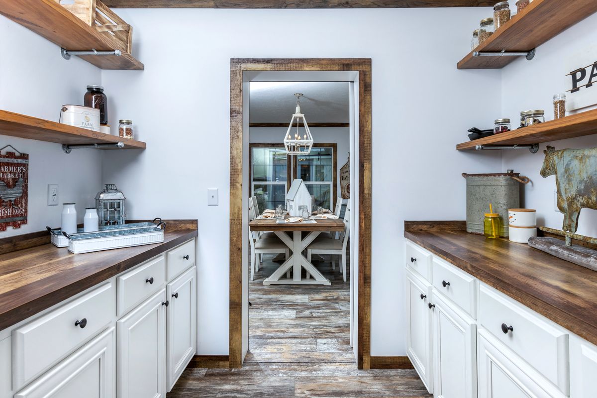 A kitchen with white cabinets and wooden shelves.