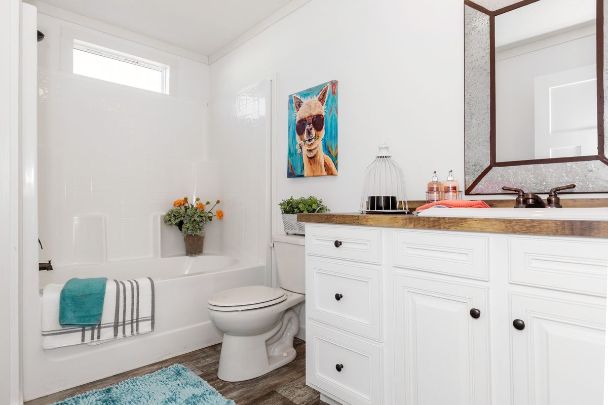 A bathroom with white cabinets and a blue rug.