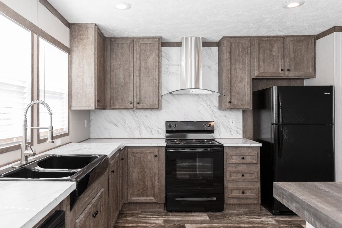 A kitchen in a mobile home with wood cabinets and black appliances.