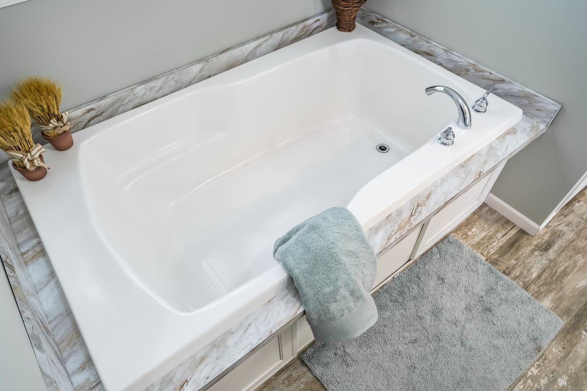8633e407-e35c-4056-a02a-e3cc0291bc39 A white bathtub in a bathroom with hardwood floors.