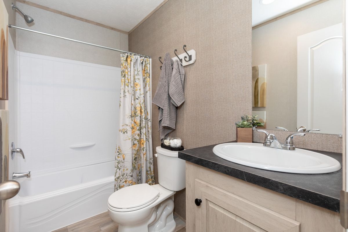 87727775-3c05-49c1-a187-d8fde9563d1d A bathroom with a toilet, sink and shower.