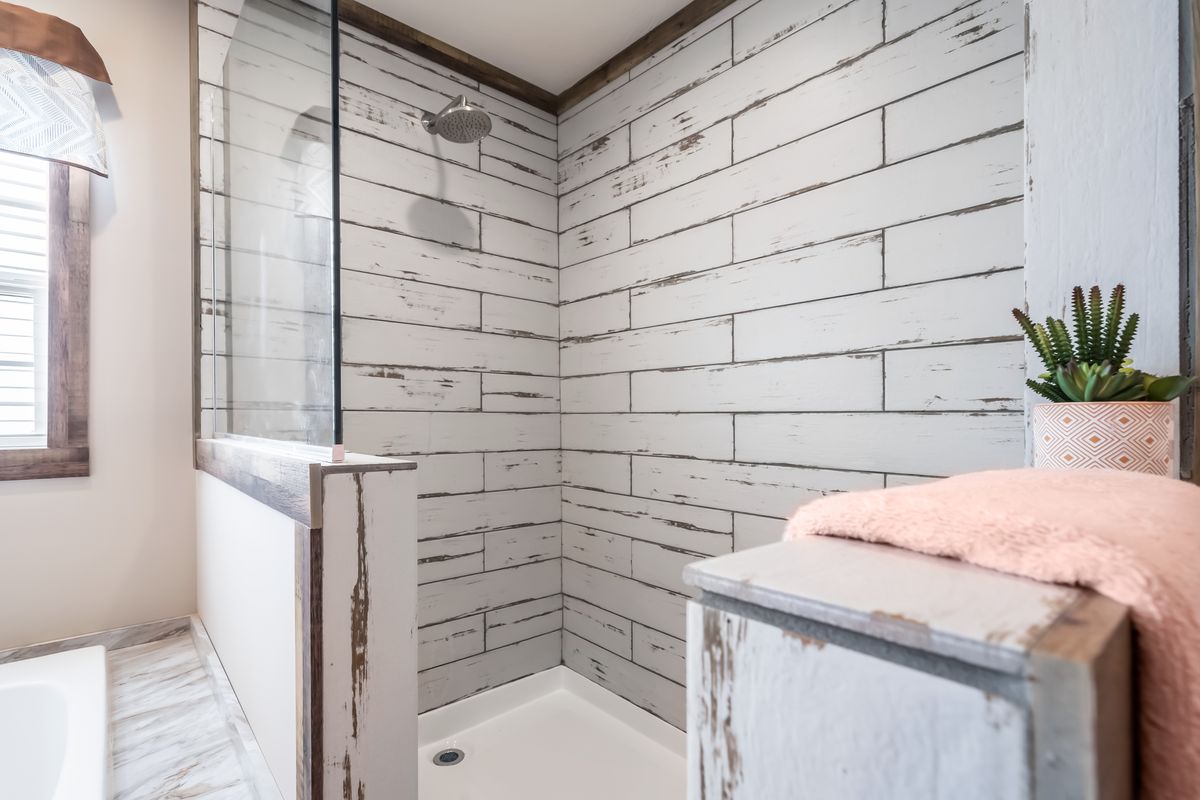 A bathroom with a white shower stall and a pink towel.