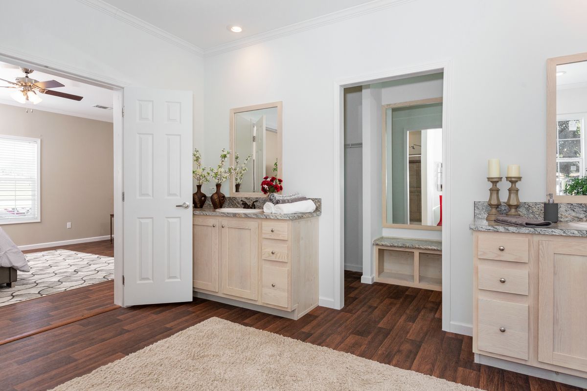 A white bathroom with hardwood floors and a ceiling fan.