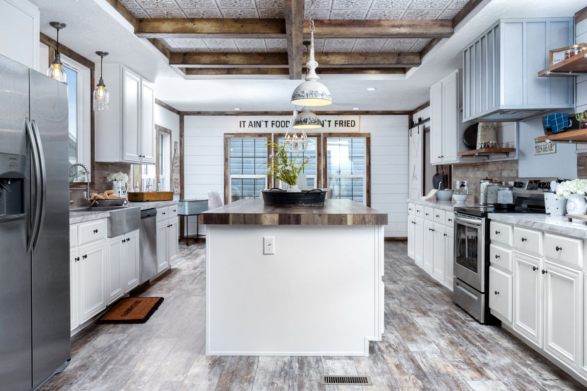 A kitchen with white cabinets and wood floors.