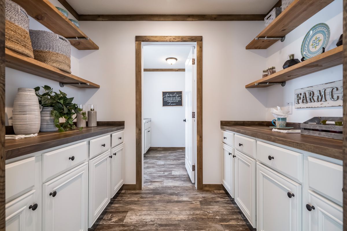 92ec8825-f477-48ae-9d77-77bceb857ff7 A small kitchen with white cabinets and wood floors.