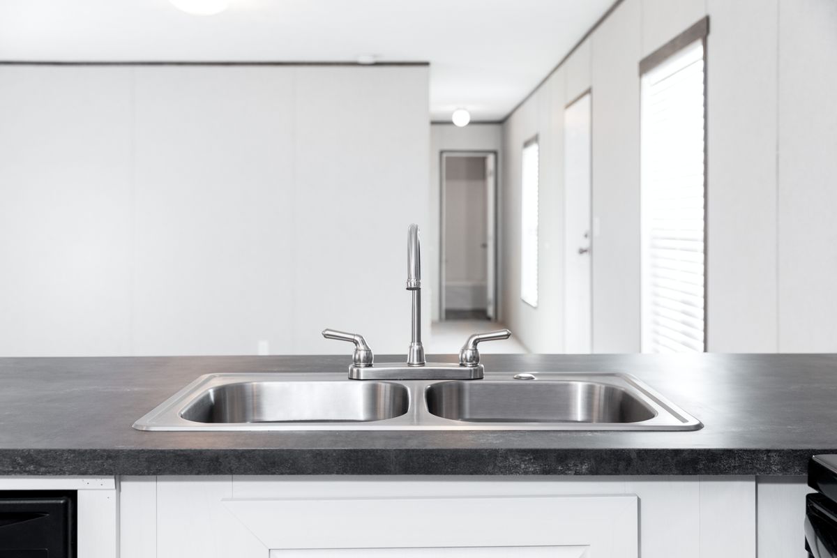 9620bf2d-eeb7-4ea3-a5ae-c9c0c822e4ca A kitchen with a stainless steel sink and black counter tops.