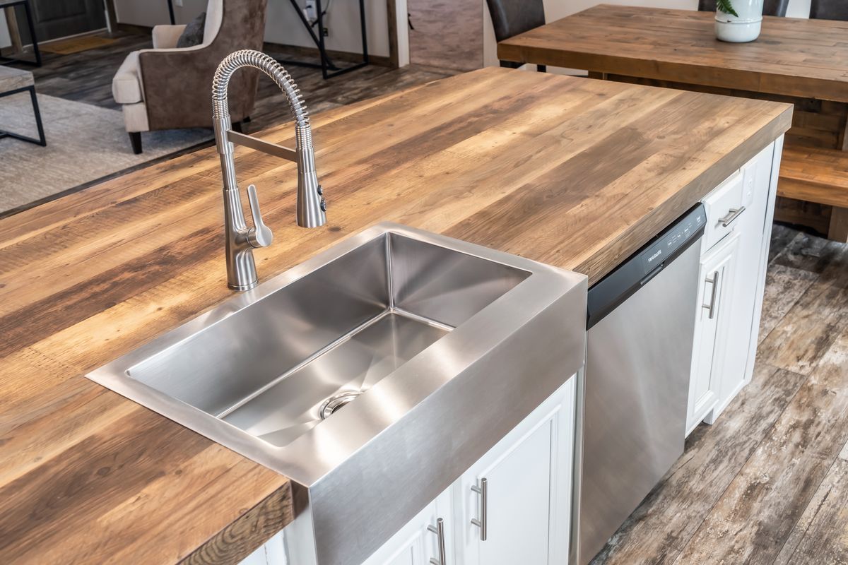 A kitchen with a wooden counter top and stainless steel sink.