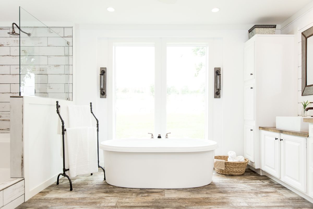 A white bathroom with wood floors and a tub.