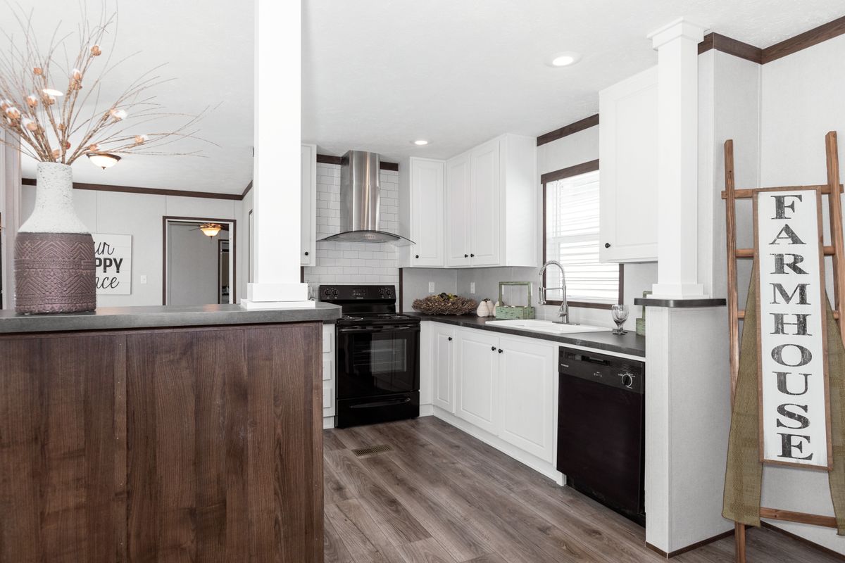 A kitchen in a mobile home with a farmhouse sign.