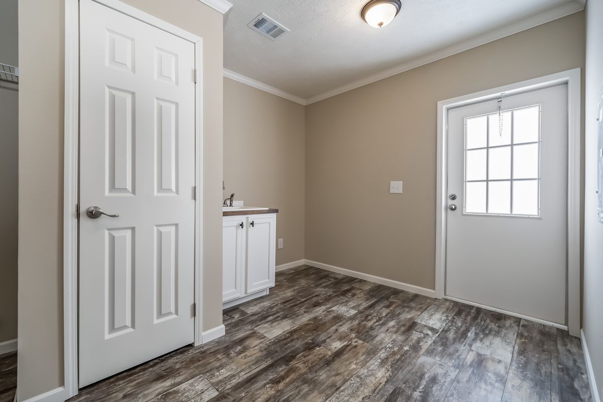 9b0d8fbf-4583-4a6f-b7fa-de702f6ef265 An empty room with wood floors and a white door.