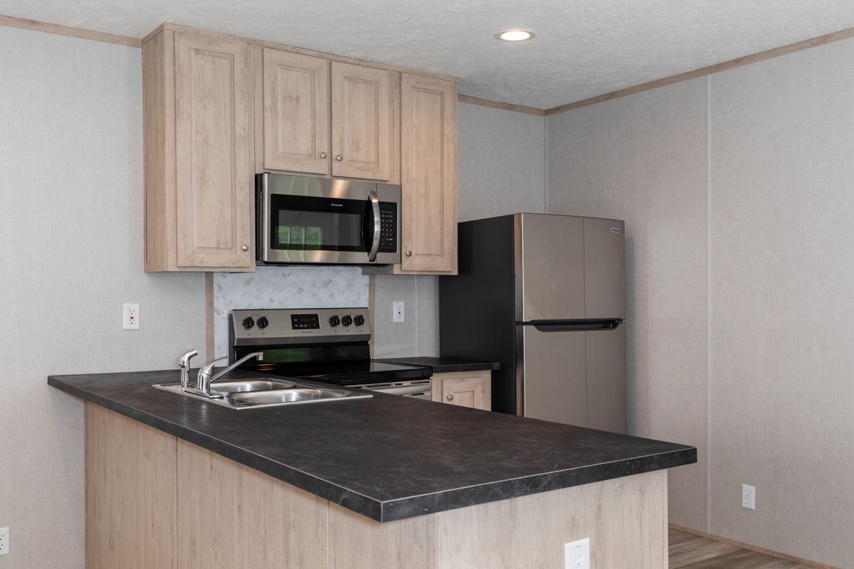 9e306eab-ae28-402c-b22d-e36e1fa37e64 A kitchen in a mobile home with stainless steel appliances.