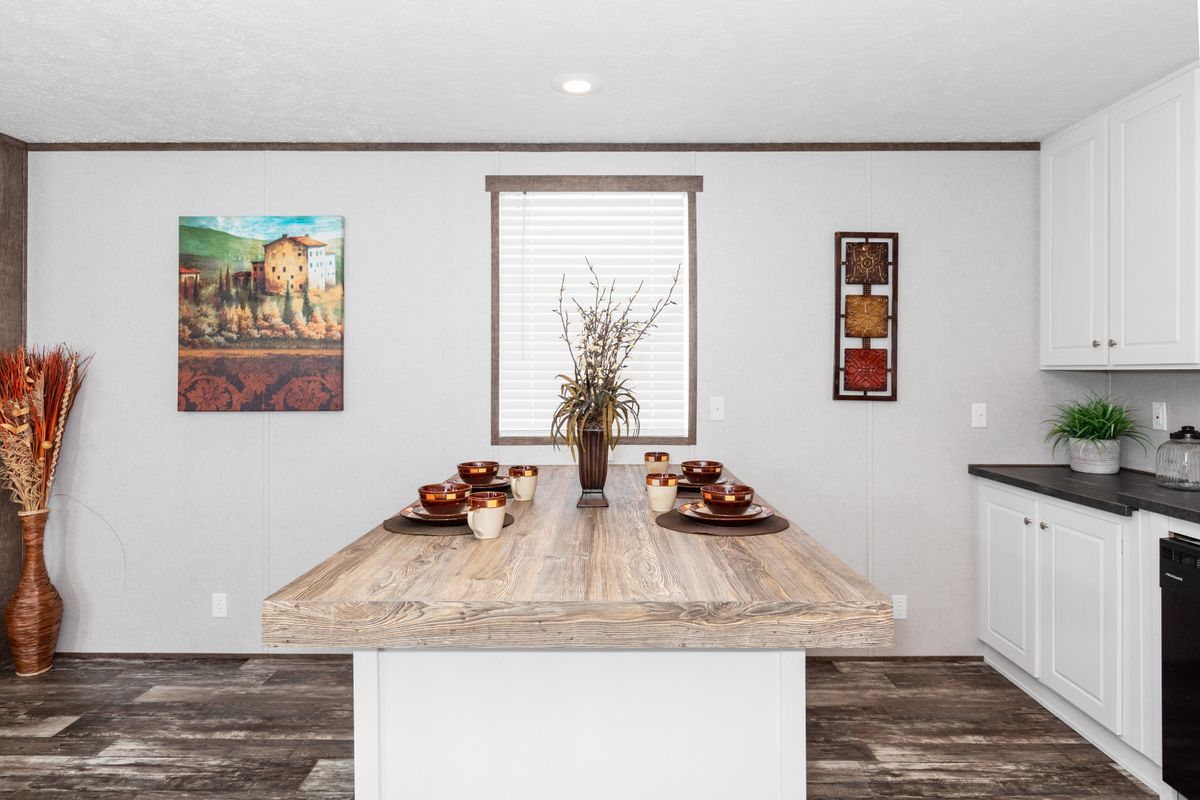 A kitchen in a mobile home with hardwood floors.