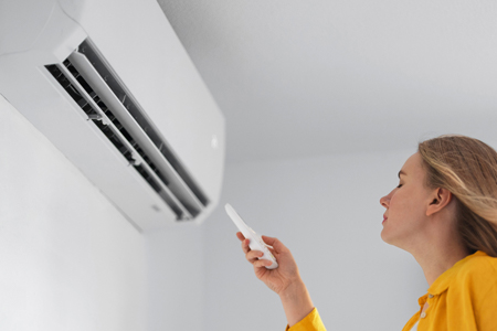 Woman turning on air conditioner