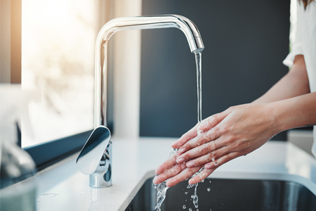 Person washing hand in kitchen sink