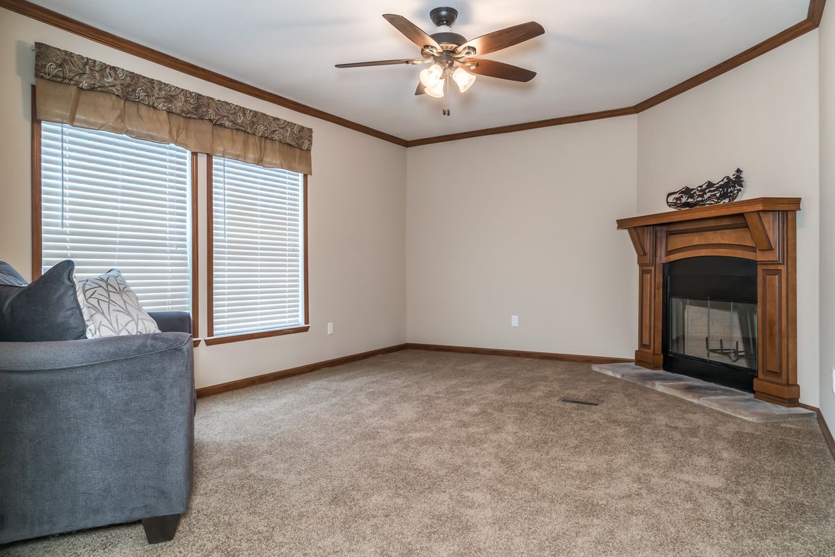 A living room with a fireplace and ceiling fan.