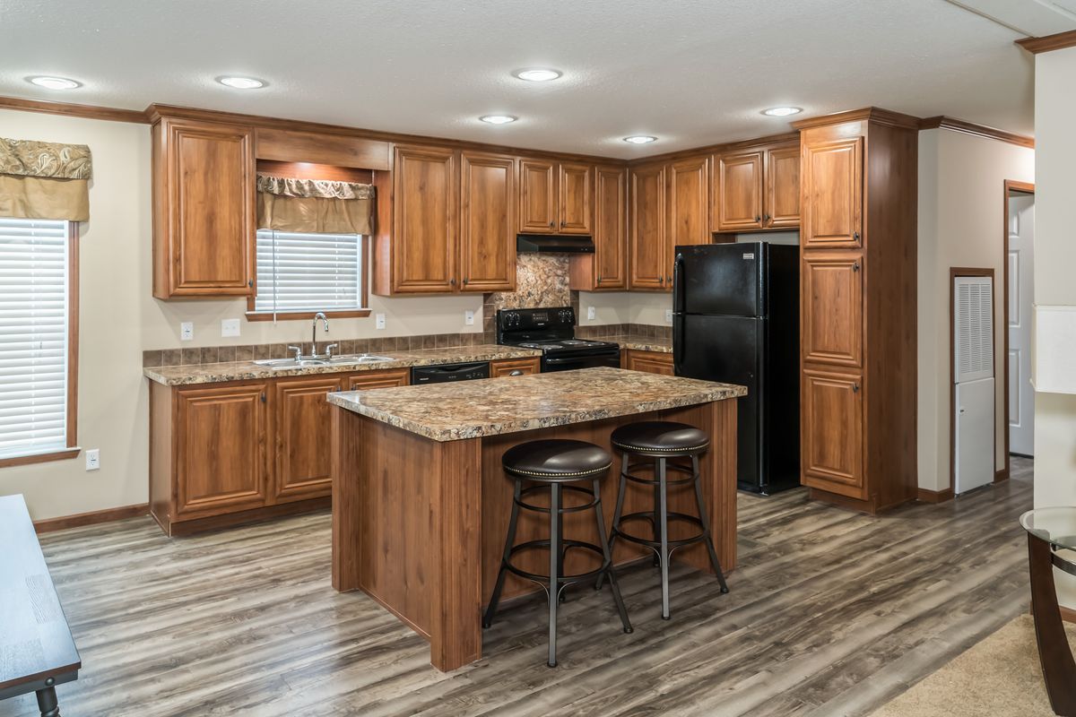 A kitchen in a mobile home with wood cabinets and granite counter tops.