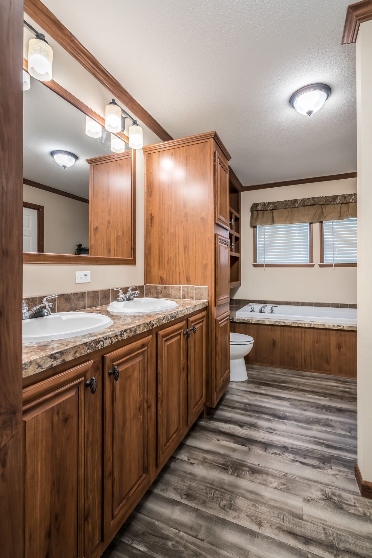 A bathroom with wood cabinets and granite counter tops.