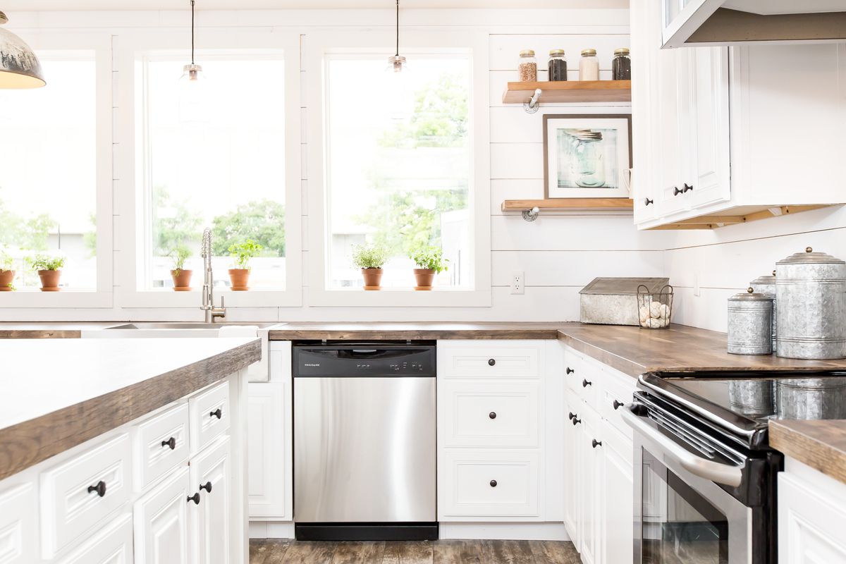 A white kitchen with wood floors and stainless steel appliances.