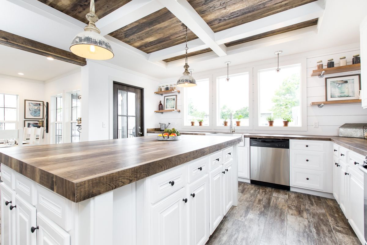 A white kitchen with wood beams and wood counter tops.