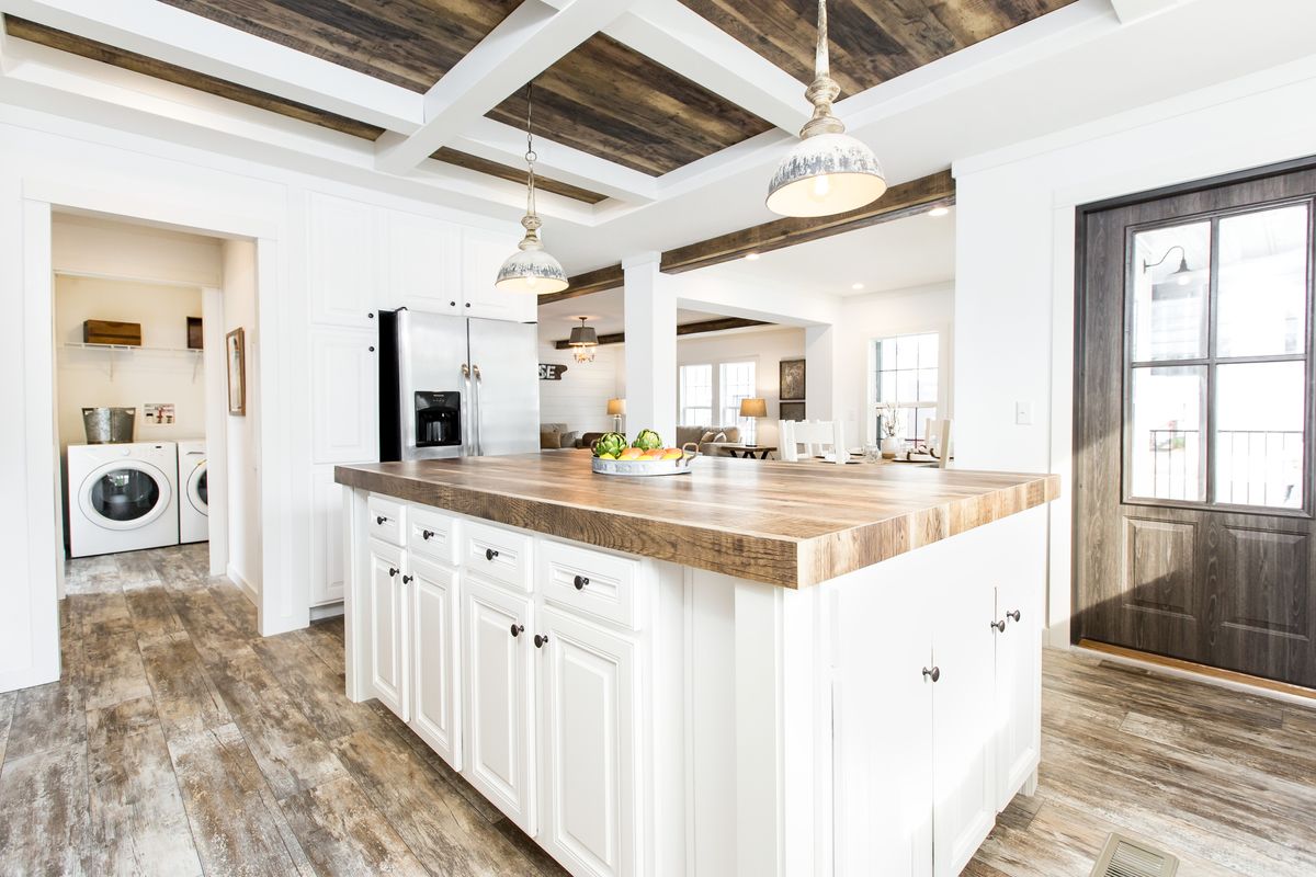A white kitchen with wood floors and a washer and dryer.