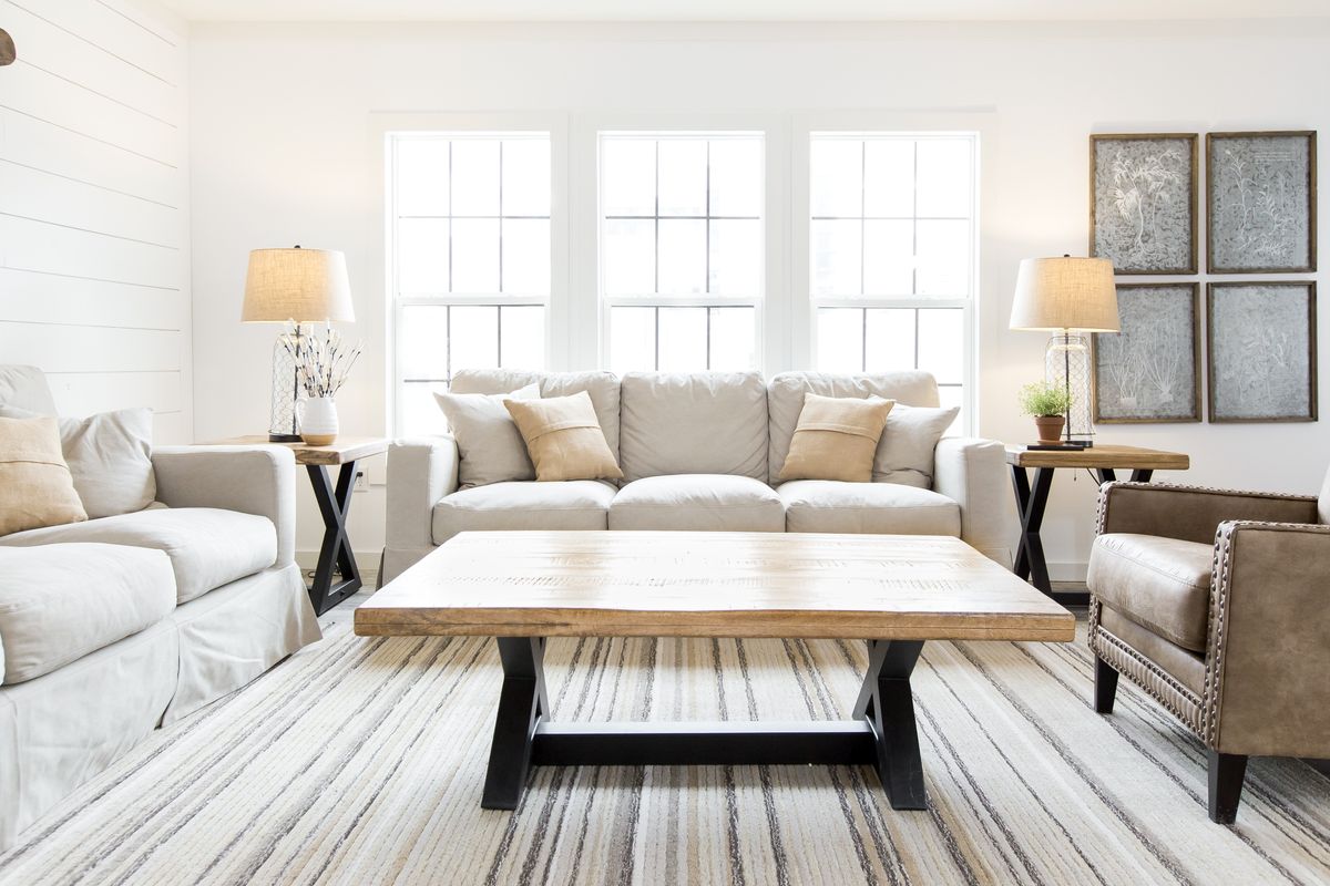 A living room with white furniture and a striped rug.