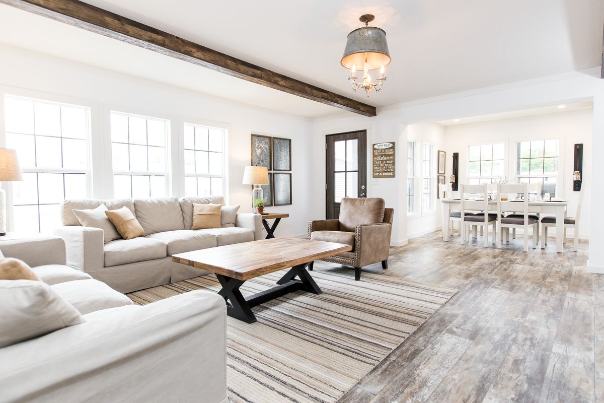 A living room with wood beams and white furniture.