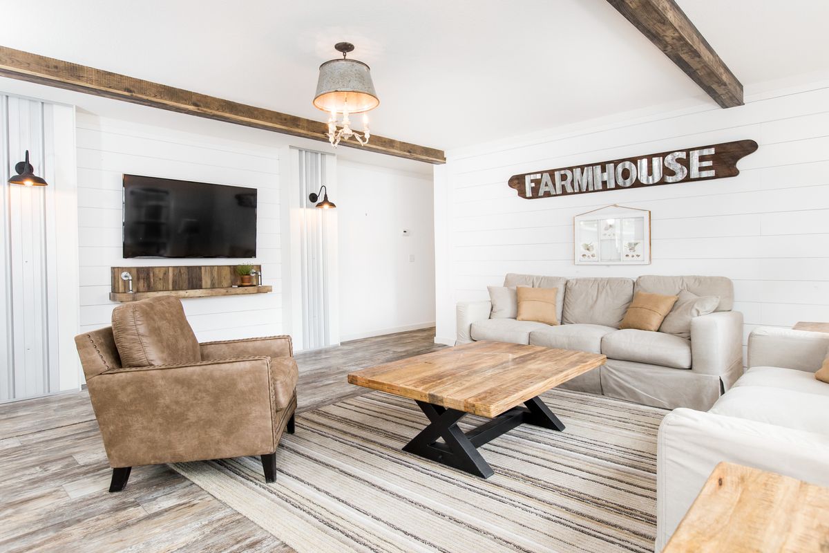A living room with wood beams and a farmhouse sign.