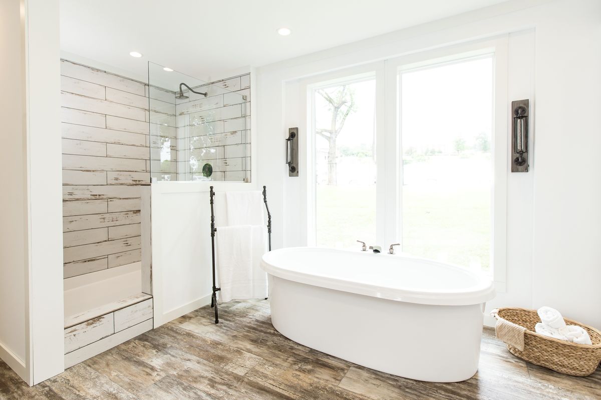 A white bathroom with wood floors and a tub.