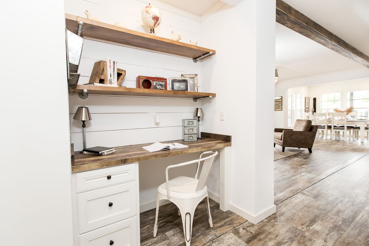 A white desk with a wooden shelf in a home office.